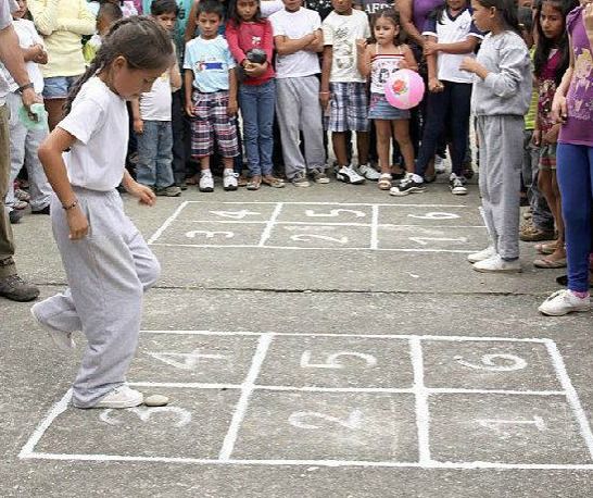 Children playing hopscotch (rayuela) on a sidewalk